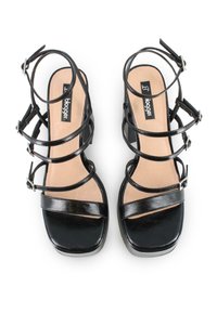 Sandalias de tacón alto negras que presentan múltiples tiras delgadas, hebillas ajustables y un acabado de charol suave. Diseño de punta cuadrada con una plantilla acolchada.