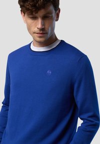 Maglione blu reale a collo rotondo realizzato in un morbido tessuto a maglia, con un piccolo logo tono su tono sul petto e polsini a coste.