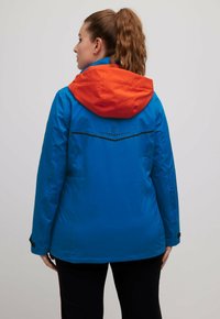 Blauw waterdichte jas met een oranje capuchon, voorzien van een strak ontwerp, textuurstof en zwarte details op de rug.