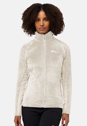 Giacca in fleece beige chiaro con colletto alto, zip frontale e tasche laterali. Texture morbida, vestibilità slim e dettaglio logo discreto sul petto.
