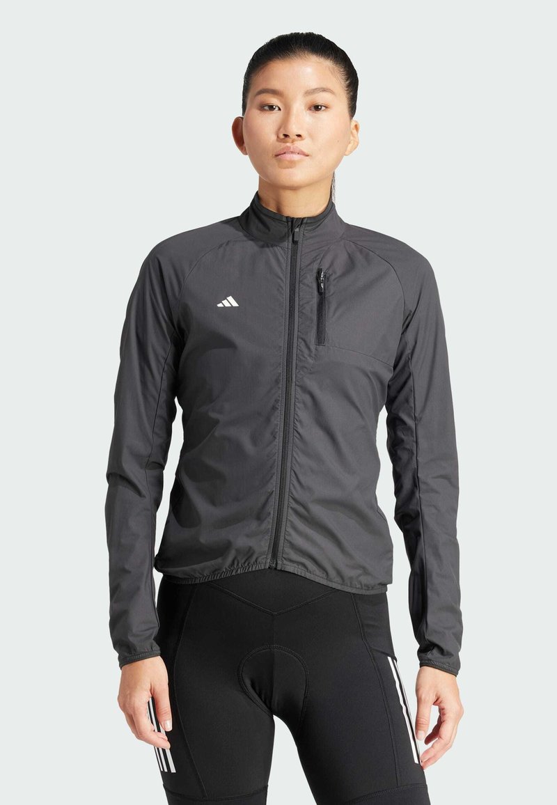 Lekka czarna kurtka z wysokim kołnierzem, przednim zamkiem błyskawicznym i zamkniętą kieszenią na piersi. Posiada białe logo Adidas oraz teksturowany materiał.