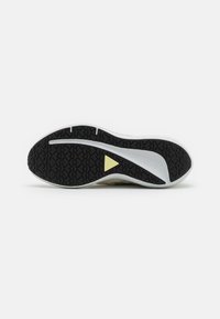 Suela de zapato con un fondo de goma negra texturizada, que presenta una entresuela blanca y un acento triangular amarillo en el centro.