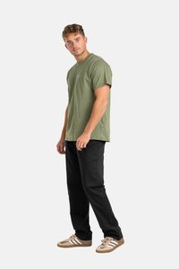 Camiseta de manga corta color verde oliva con cuello redondo, combinada con pantalones negros y zapatillas marrones con franjas blancas. Corte estándar, material de algodón.