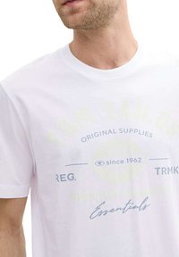 T-shirt en coton blanc avec texte imprimé en bleu clair et jaune, col rond, manches courtes, design ajusté et sans motifs visibles.