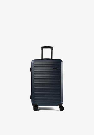 Dunkelblauer Hartschalenkoffer mit horizontalen Rillen, ausgezogenem ausziehbarem Griff und vier Spinner-Rädern auf weißem Hintergrund.