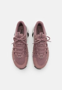 Lichtroze sport schoenen met een textuur geventileerde bovenkant, vetersluiting en een witte dempende zool. Bevat branding op de tong en de zijkant.