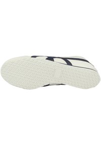 Sneaker con una suola in gomma testurizzata, caratterizzato da una base bianca e linee di design blu scuro sulla parte superiore. La suola esterna ha una presa a motivo.