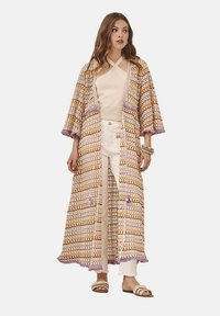 Kimono largo y abierto por delante, hecho de tela tejida multicolor con patrones en oro, morado y crema, que presenta mangas anchas y detalles de flecos.