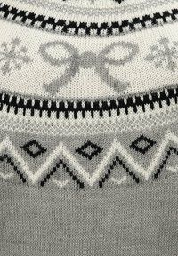 Pull en tricot gris avec des motifs noir et blanc, incluant des flocons de neige et des diamants, avec un design de ruban au niveau du col.