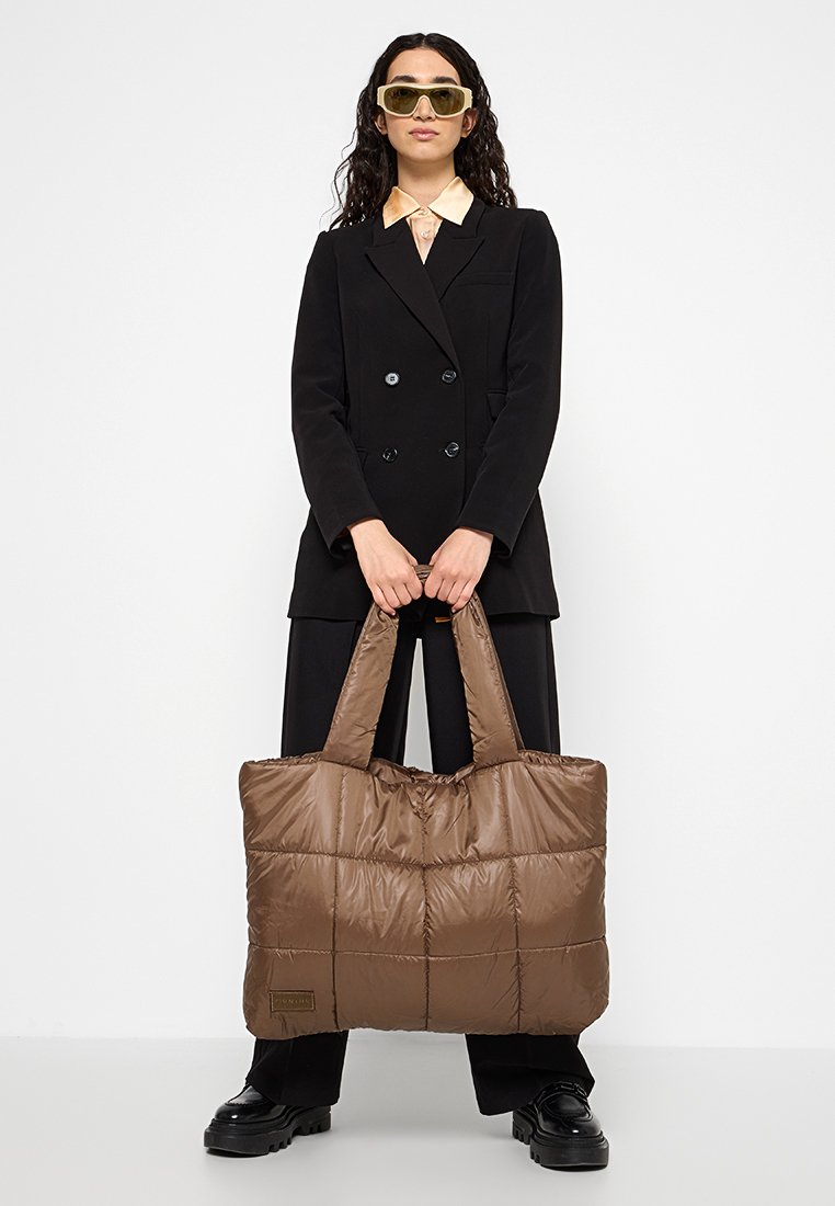 Braune, gesteppten Tragetasche mit gepolsterter Textur, großer rechteckiger Form und robusten Griffen. Verfügt über eine Logo-Akzent auf der Vorderseite.