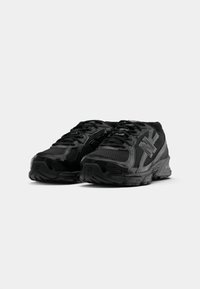 Baskets de sport noires avec une tige en mesh, un design à lacets, un logo bien en évidence et une semelle en caoutchouc texturée pour l'adhérence.