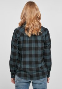 Camicia in flanella a scacchi nera e turchese con maniche lunghe, polsini bottonati e colletto a punta. Tessuto morbido e design a vestibilità rilassata.