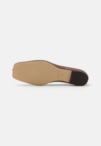 Semelle de chaussure en cuir marron avec une forme lisse et légèrement courbée. Semelle en caoutchouc texturé au talon, étiquetée "ALOHA" et taille "37."