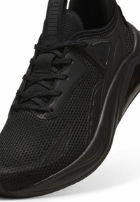Zwarte sportieve schoen met een gemêleerde mesh bovenkant, synthetische accenten, een ronde neus en een gezoneerde zool voor ondersteuning.