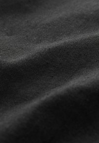 Tessuto nero con una superficie liscia e leggermente texturizzata, che mostra sottili variazioni di luce e ombra attraverso le dolci pieghe.