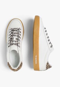 Zapatillas blancas con acentos de estampado de leopardo en el talón y los cordones, con una suela de goma marrón texturizada y ojales plateados para los cordones.
