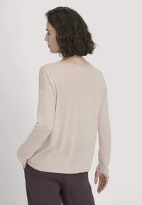 Helles rosa gestricktes Sweatshirt mit lockerer Passform, langen Ärmeln und weitem Halsausschnitt. Glatte Textur, gerippter Saum und lässiger Stil.