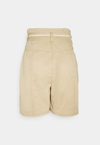Short beige taille haute avec une taille style sac en papier et une fine ceinture en corde blanche, vue de dos sur un fond clair uni.
