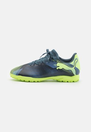 Scarpa sportiva di colore blu scuro con suola verde brillante. Presenta una parte superiore texturizzata con motivi a strisce blu e verdi. Design con chiusura a lacci.