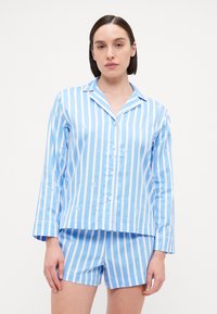 Blauw-wit gestreept pyjamastel met een lange mouw en knoopsluiting aan de bovenkant en shorts. De stof heeft een herhalend logopatroon. Soepele textuur.