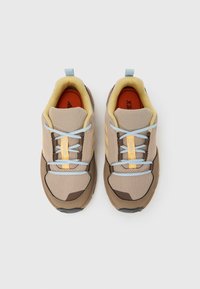 Μπεζ αθλητικά παπούτσια με πλεκτό επάνω μέρος, καφέ λεπτομέρειες, γαλάζια κορδόνια και πορτοκαλί πάτο με την επιγραφή "TERREX." Υφή στη σόλα.