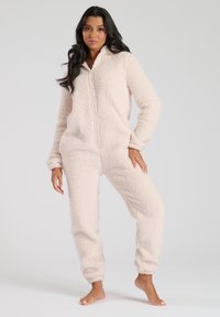 Fuzzy roze onesie van pluizig materiaal met een rits aan de voorkant, lange mouwen en elastische boorden en enkels, met een zachte, textuurvolle oppervlakte.