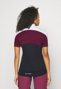 T-shirt de sport à manches courtes en blanc, bordeaux et noir. Panneau arrière texturé. Logo situé à l'ourlet inférieur. Comprend un col montant.