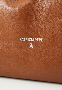 Brun teksturert skinnhåndveske med en glatt overflate. Har hvit "PATRIZIA PEPE"-logo og et karakteristisk insektikon.
