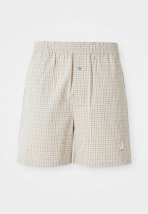 Shorts à carreaux beige clair avec une texture douce, ceinture élastique et broderie décorative d'oie blanche près de l'ourlet.