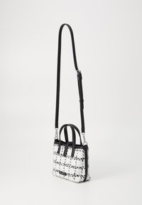 Sac à main en tweed noir et blanc avec des poignées doubles et une bandoulière réglable. Il présente une surface texturée avec un motif à carreaux et des accents en métal argenté.