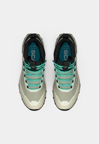 Hallid ja kreemjad matkajalanõud türkiissiniste paeltega, tekstureeritud musta tallaga, pehmendusega krae ja sinise sisetallaga, millel on kaubamärgi logo.