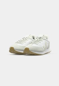 Lysfargede sneakers med en kombinasjon av mesh- og semsket skinnmaterialer, rund tå, teksturert såle, og minimale merkevare-aksenter.