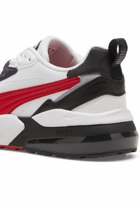 Talons de baskets Puma blancs, noirs et rouges avec semelle épaisse, dessus en mesh et cuir, et languette arrière siglée.