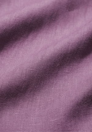 Prim-plan al unui material moale, texturat, de culoare mov, cu un model de țesătură vizibil și pliuri delicate care creează profunzime și umbre.