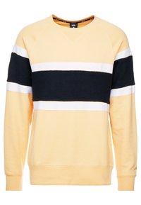 Mjukissweater i ljusgul med ett brett svart horisontellt rand, kantat av vita ränder, över bröstet och ärmarna.