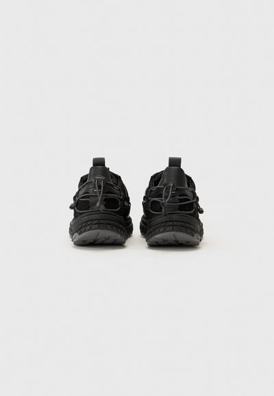 Black shoes featuring a lightweight mesh upper, elastic laces, and a textured rubber sole with a distinctive tread pattern.
