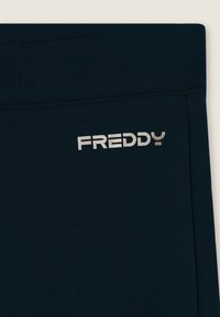 Tessuto blu navy con una superficie liscia. Presenta un logo argento "FREDDY" sul lato. Design semplice, senza motivi o accenti aggiuntivi.