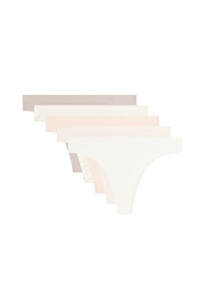 Partie inférieure du torse d'une femme portant une culotte bikini beige sans coutures sur fond blanc.