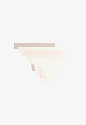 Partie inférieure du torse d'une femme portant une culotte bikini beige sans coutures sur fond blanc.