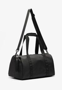 Sac de sport noir en matériau lisse, doté de deux poignées et d'une bandoulière réglable. Conception simple sans motifs ni accessoires.