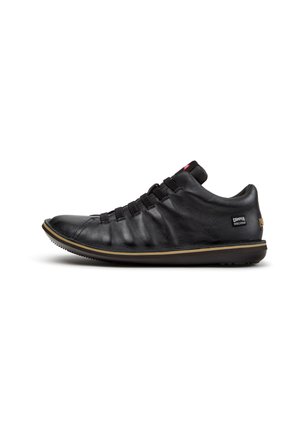Sneaker basso in pelle nera con suola in gomma, passanti elastici per i lacci e piccola etichetta del marchio Camper sul lato e sul tallone.