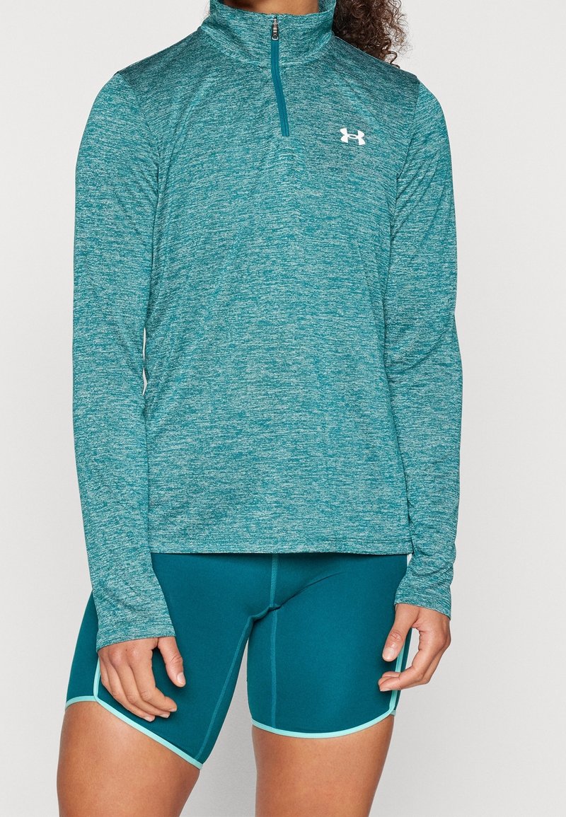 Teal långärmad ziptröja i texturerat tyg, i kombination med figursydda teal shorts med kontrasterande ljusblå kant.