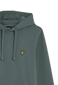 Hoodie in gedempt groene stof met een textuurafwerking, verstelbare trekkoorden en een klein geel geborduurd logo op de borst.