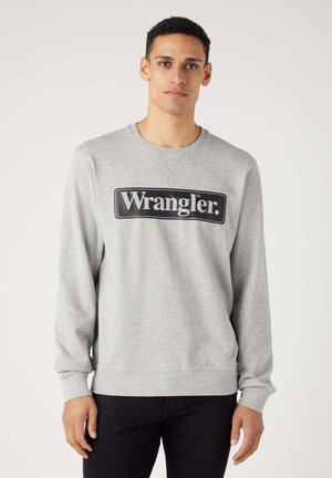Felpa grigia realizzata in tessuto morbido, con colletto rotondo, maniche lunghe e un logo rettangolare nero "Wrangler." al centro.