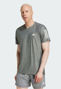 Camiseta deportiva en gris oscuro, de manga corta, con un tejido texturizado y el logo blanco de Adidas en el pecho y tres franjas blancas en el hombro.