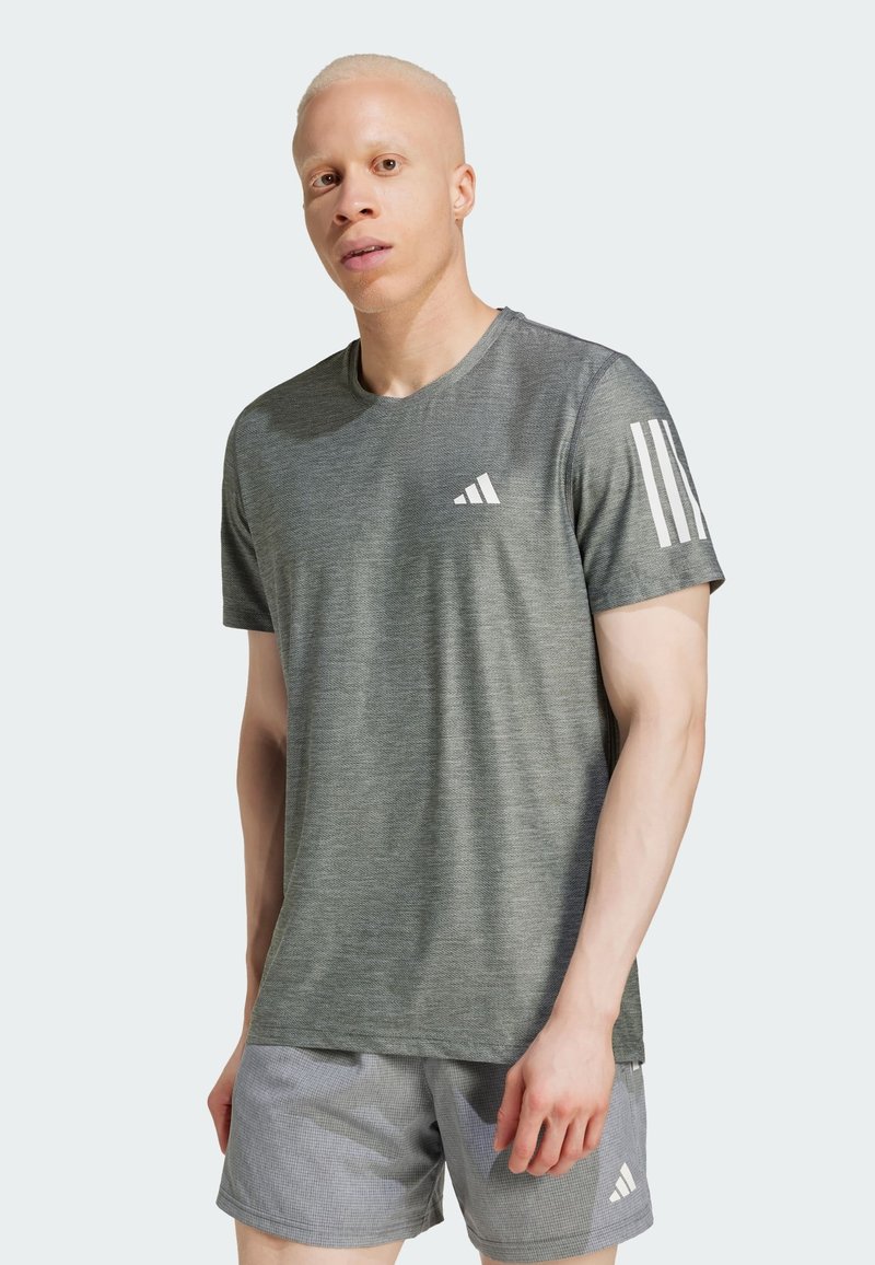 Camiseta deportiva en gris oscuro, de manga corta, con un tejido texturizado y el logo blanco de Adidas en el pecho y tres franjas blancas en el hombro.