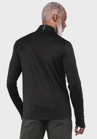 Schwarzes Langarmshirt mit hohem Kragen, das eine glatte Textur aufweist und ein grünes Akzentdetail auf dem Rücken hat.