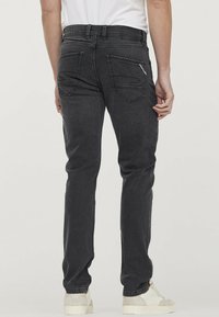 Donkergrijze denim jeans met een slim fit, voorzien van twee achterzakken en een logo patch op de tailleband. Textuurstof, minimale slijtage.