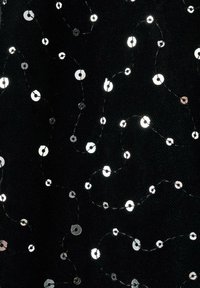 Svart tyg med silverfärgade paljetter i ett vågigt mönster, sammanbundna med tunna svarta trådar, vilket skapar en texturerad, glittrande yta.