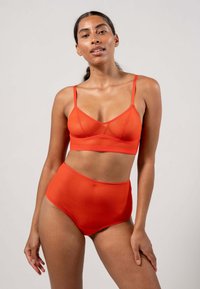 Röd sömlös bralette och högmidjade trosor, tillverkade av ett glatt, elastiskt tyg. Enkel design med tunna remmar och utan synliga sömmar eller mönster.